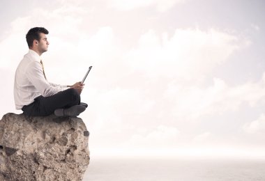 İş adamı taşın üstünde oturuyor.