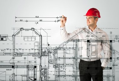 Genç bir mimar ev planı çiziyor.