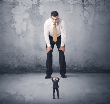 Büyük işletme zorbası küçük iş arkadaşına bakıyor.