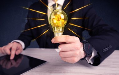 bir elektrik ampulü tutan iş kişi