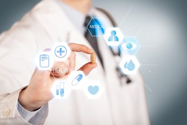 Beyazlı bir doktor elinde hap tutuyor.