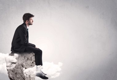 Ofis çalışanı kayanın tepesinde oturuyor.