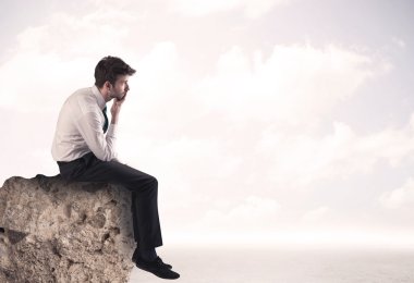 İş adamı taşın üstünde oturuyor.