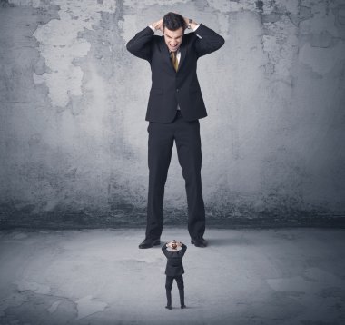Büyük işletme zorbası küçük iş arkadaşına bakıyor.