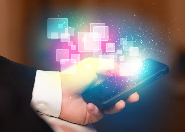 Hand holding smart phone with abstract glowing squares — Stock Photo, Image