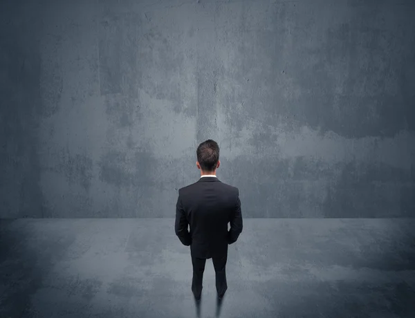 Businessman standing in front of urban wall — Stock Photo, Image