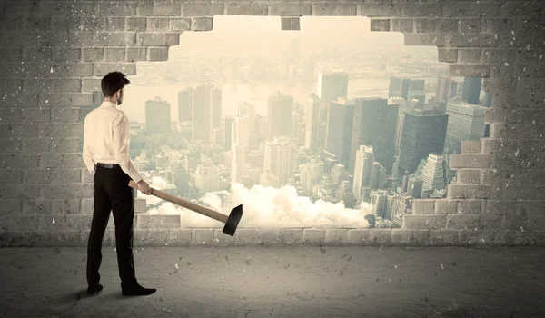 Hombre de negocios golpeando la pared con martillo en la vista de la ciudad — Foto de Stock
