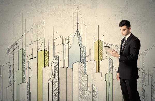 Businessman standing with drawn cityscape — Stock Photo, Image