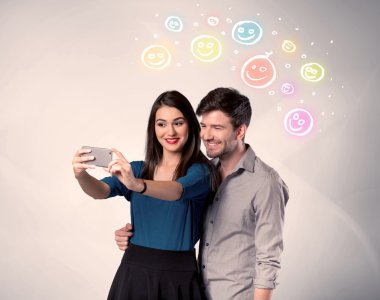 Mutlu çift gülen yüzle selfie çekiyor.