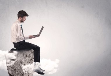 Ofis çalışanı kayanın tepesinde oturuyor.