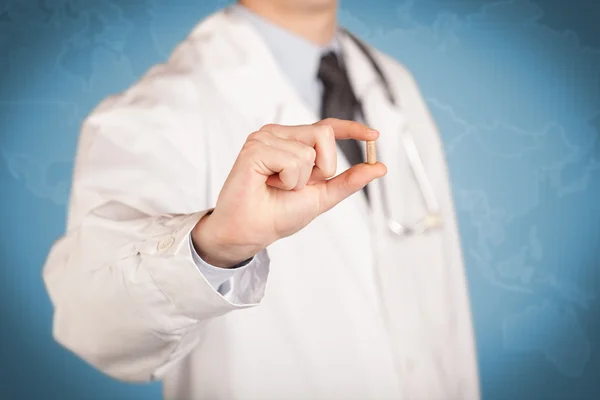 Doctor en blanco sosteniendo una píldora — Foto de Stock