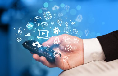 Medya simgeleri ve sembolleriyle el ele tutuşan akıllı telefon 