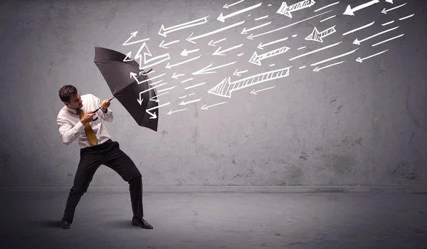 Hombre de negocios de pie con paraguas y flechas dibujadas golpeándolo —  Fotos de Stock