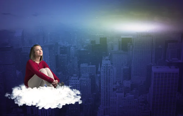 Kobieta siedzi na chmury nad miastem — Zdjęcie stockowe