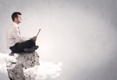 Ofis çalışanı kayanın tepesinde oturuyor.