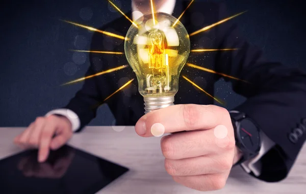 Business person holding an electric light bulb — Stock Photo, Image