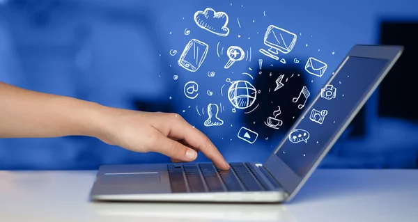 Hand writing on notebook computer with media icons — Stock Photo, Image