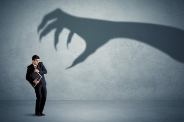 Business person afraid of a big monster claw shadow concept clipart