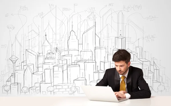 Бизнесмен, сидящий за белым столом с нарисованными вручную зданиями — стоковое фото