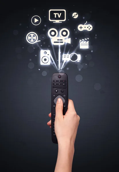 Hand with remote control and media icons — Stock Photo, Image