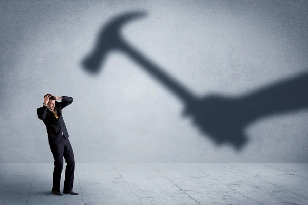 Business person afraid of a shadow hand holding hammer concept — Stock Photo, Image