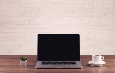 Ofis masası beyaz tuğla duvarla kapanıyor.