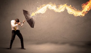 İş adamı kendini bir umbrell ile bir yangın oka savunmak