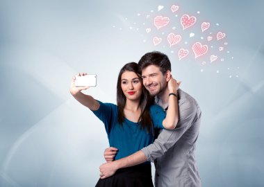 Aşık çift kırmızı kalple selfie çekiyor.