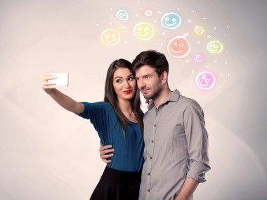 Mutlu çift gülen yüzle selfie çekiyor.