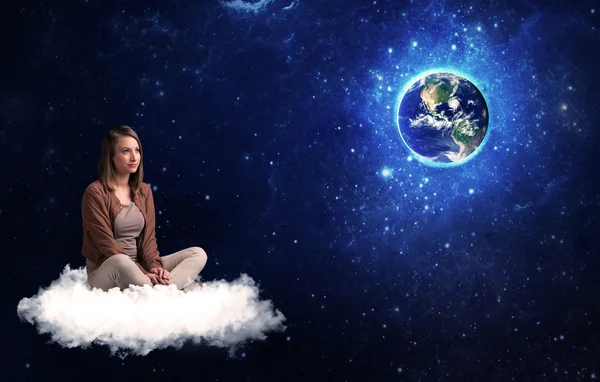 Femme assise sur un nuage regardant la planète Terre — Photo