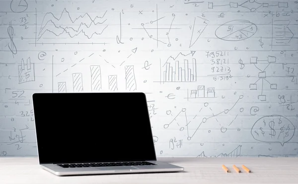 Laptop na mesa com gráficos de negócios na parede — Fotografia de Stock