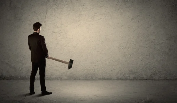 Homem de negócios em pé na frente de uma parede grungy com um martelo — Fotografia de Stock