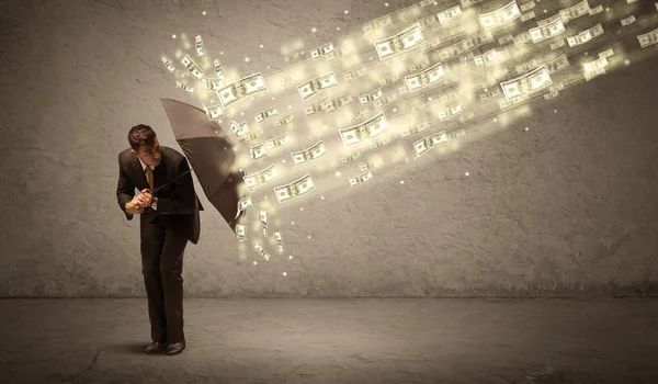 Hombre de negocios sosteniendo paraguas contra concepto de lluvia dólar — Foto de Stock