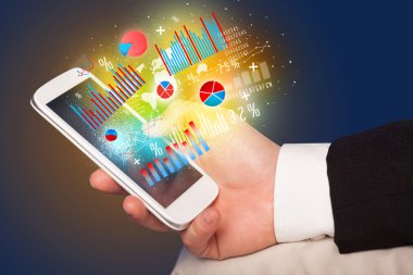 İşadamı elinde grafik sembollü akıllı telefon tutuyor.