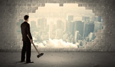 İş adamı şehir manzarasında çekiçle duvara çarpıyor