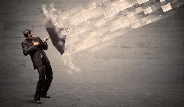 Hombre de negocios protegiendo con paraguas contra viento de papeles — Foto de Stock