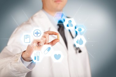 Beyazlı bir doktor elinde hap tutuyor.