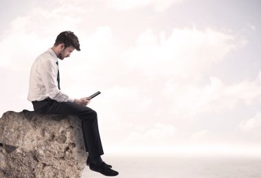 İş adamı taşın üstünde oturuyor.