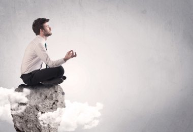 Ofis çalışanı kayanın tepesinde oturuyor.