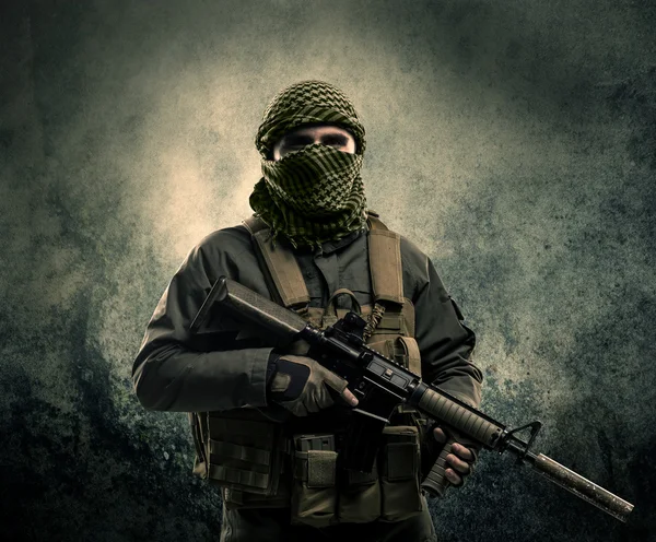 Portrait of a heavily armed masked soldier with grungy backgroun — Stock Photo, Image