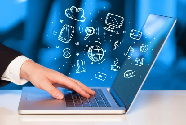 Hand writing on notebook computer with media icons — Stock Photo, Image