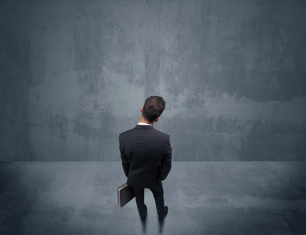 Businessman standing in front of urban wall — Stock Photo, Image