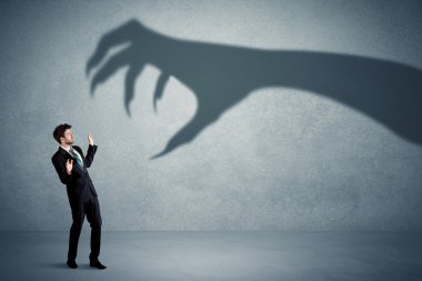 Business person afraid of a big monster claw shadow concept clipart