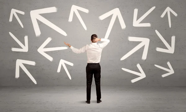 Confused salesman with arrows on wall — Stock Photo, Image