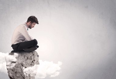 Ofis çalışanı kayanın tepesinde oturuyor.