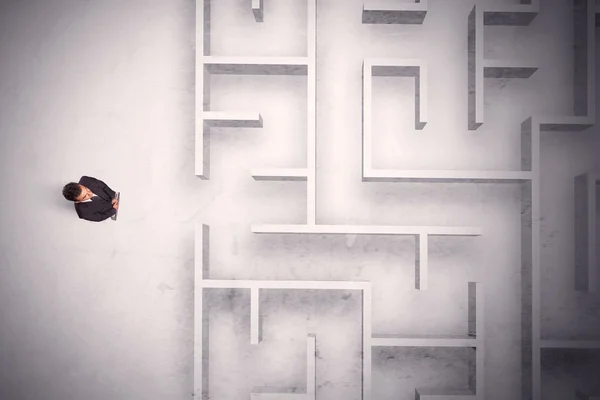 Запутавшийся бизнесмен стоит у лабиринтной стены — стоковое фото
