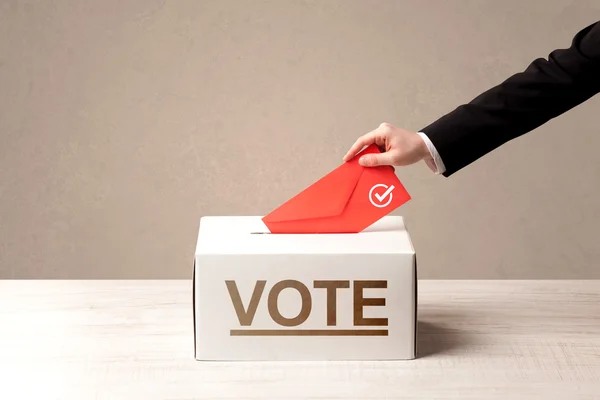 Close up of male hand putting vote into a ballot box