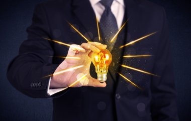 bir elektrik ampulü tutan iş kişi