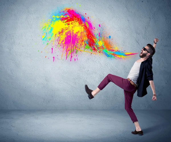 Hipster guy shouting colorful paint on wall — Stock Photo, Image