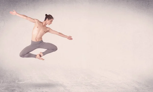 Современный артист балета, исполняющий художественный прыжок на пустом фоне — стоковое фото